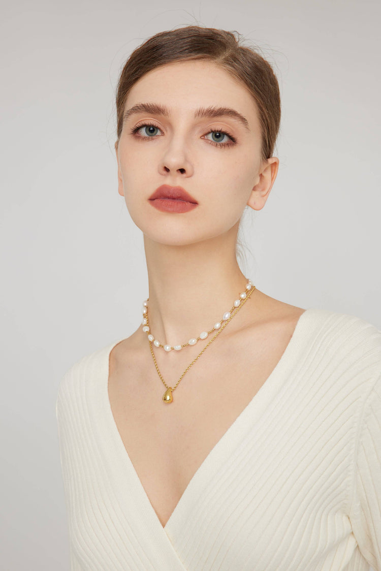 a woman wearing a necklace with pearls