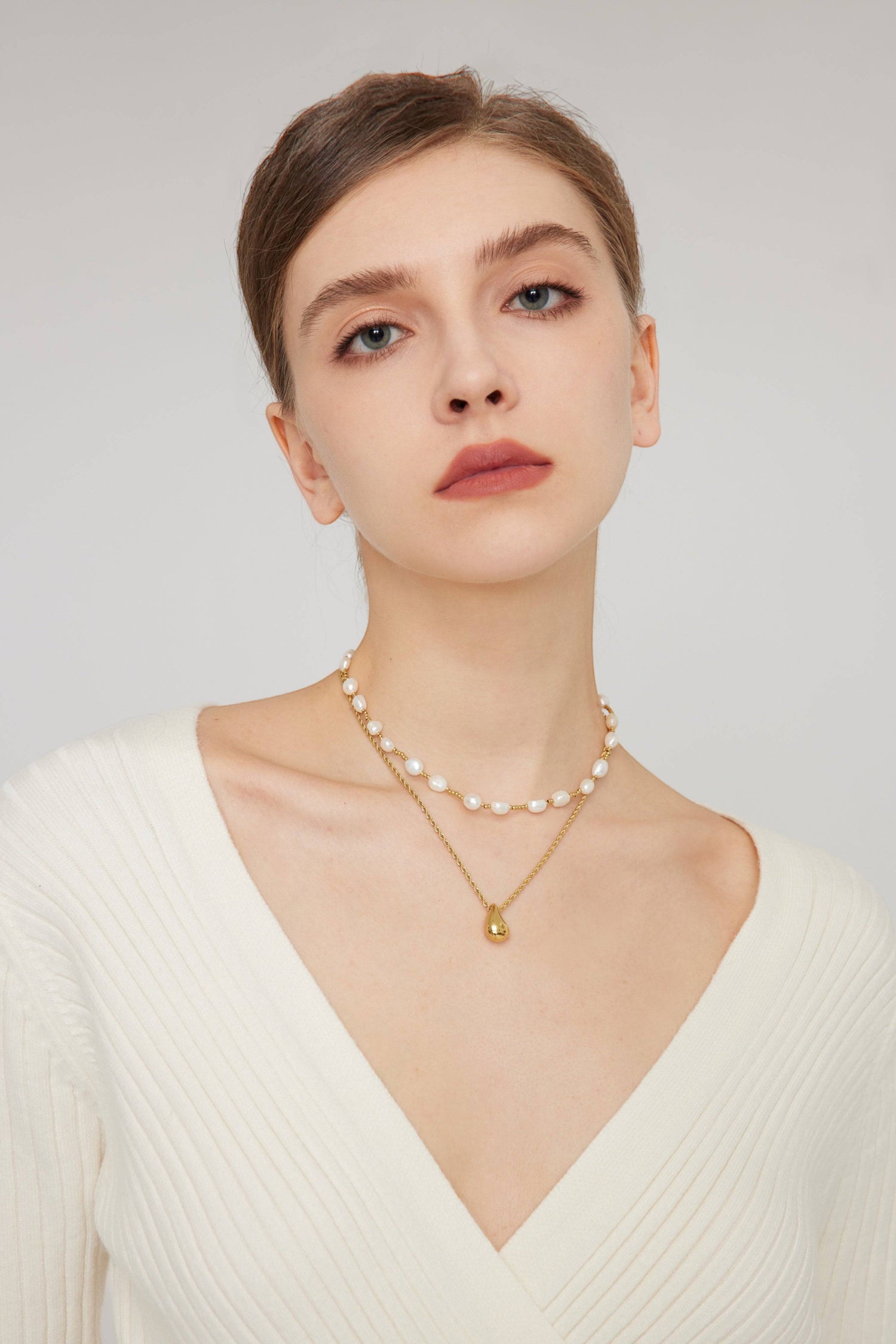 a woman wearing a necklace with pearls