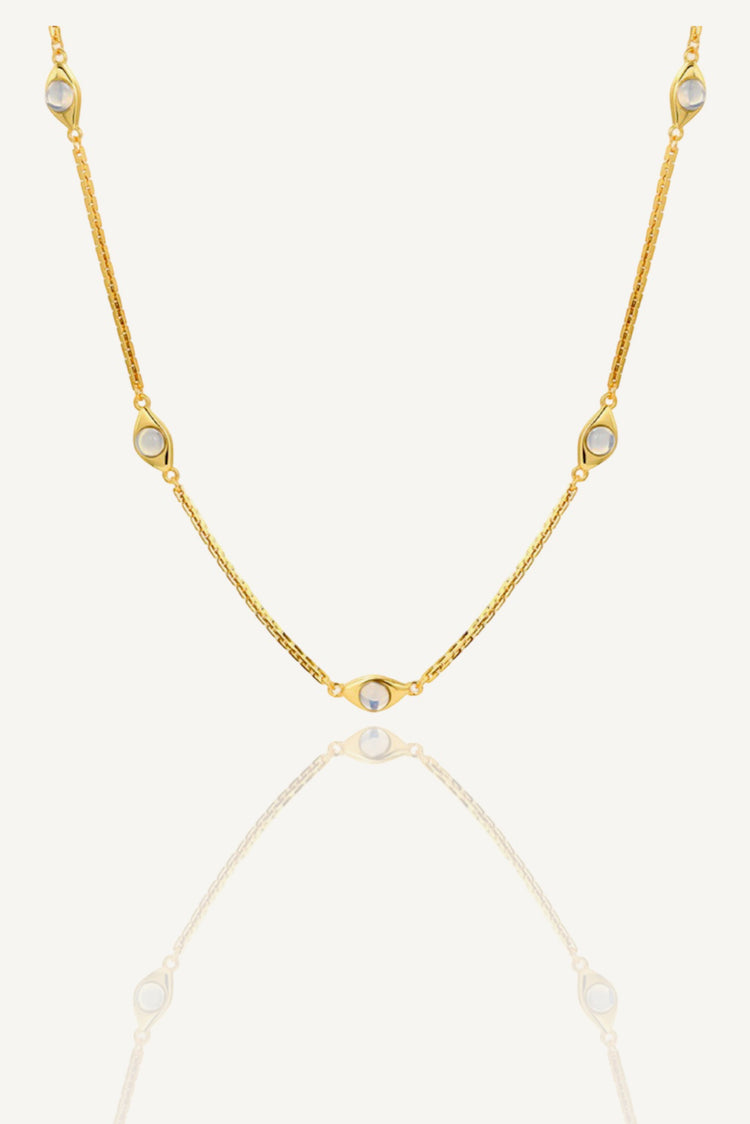 a gold chain necklace with three stones on a white background