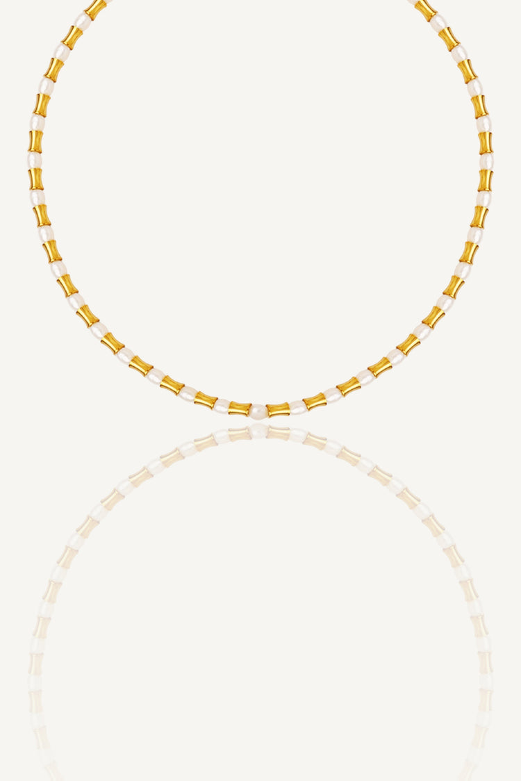 a yellow and white beaded necklace on a white background