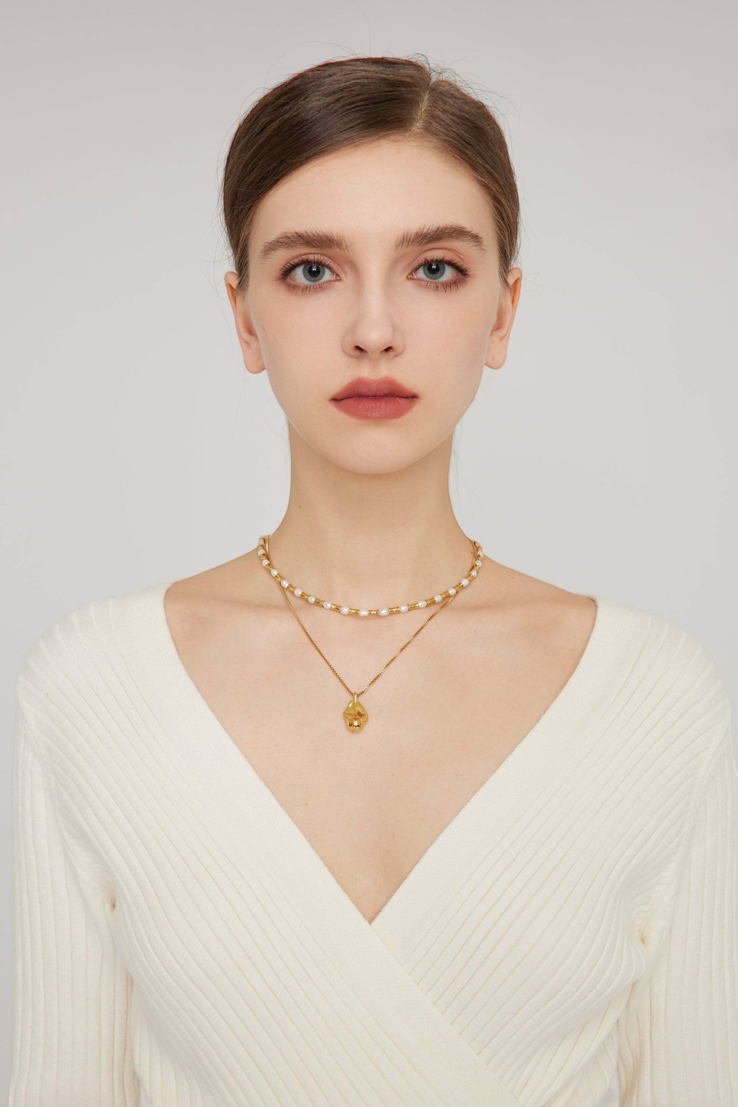 a woman wearing a white sweater and a gold necklace