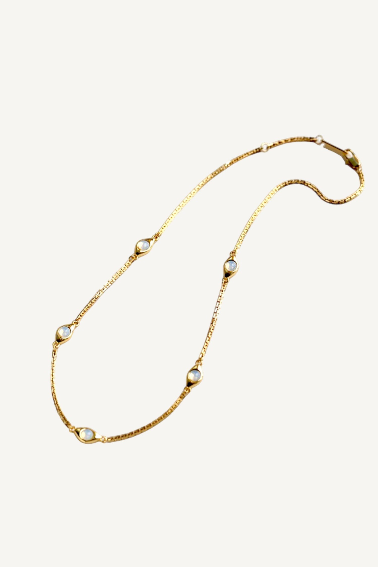 a long gold necklace with pearls on a white background