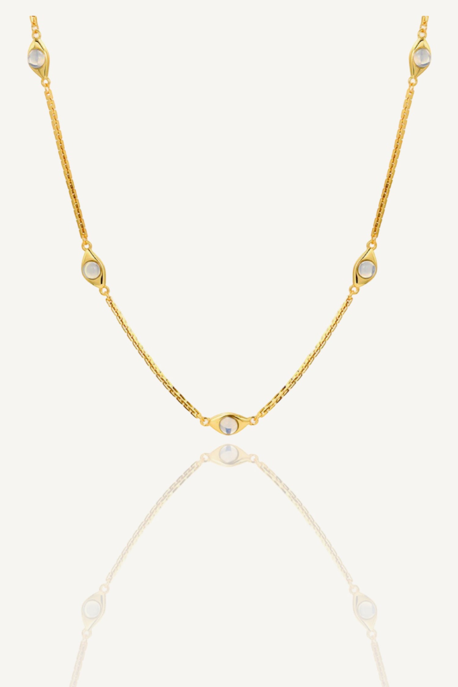 a gold chain necklace with three stones on a white background