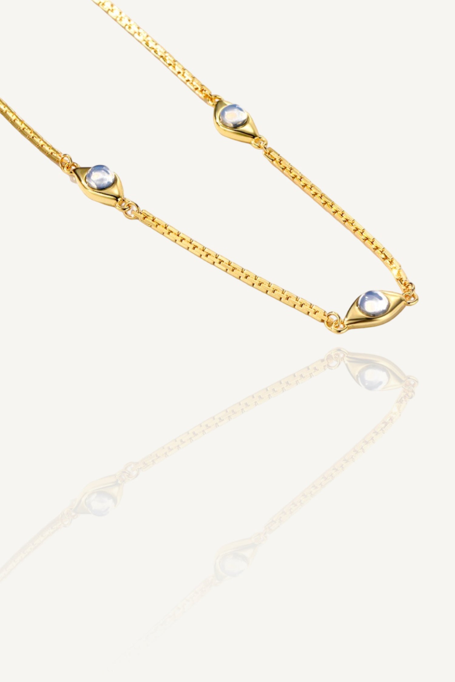 a gold chain with two pearls on it