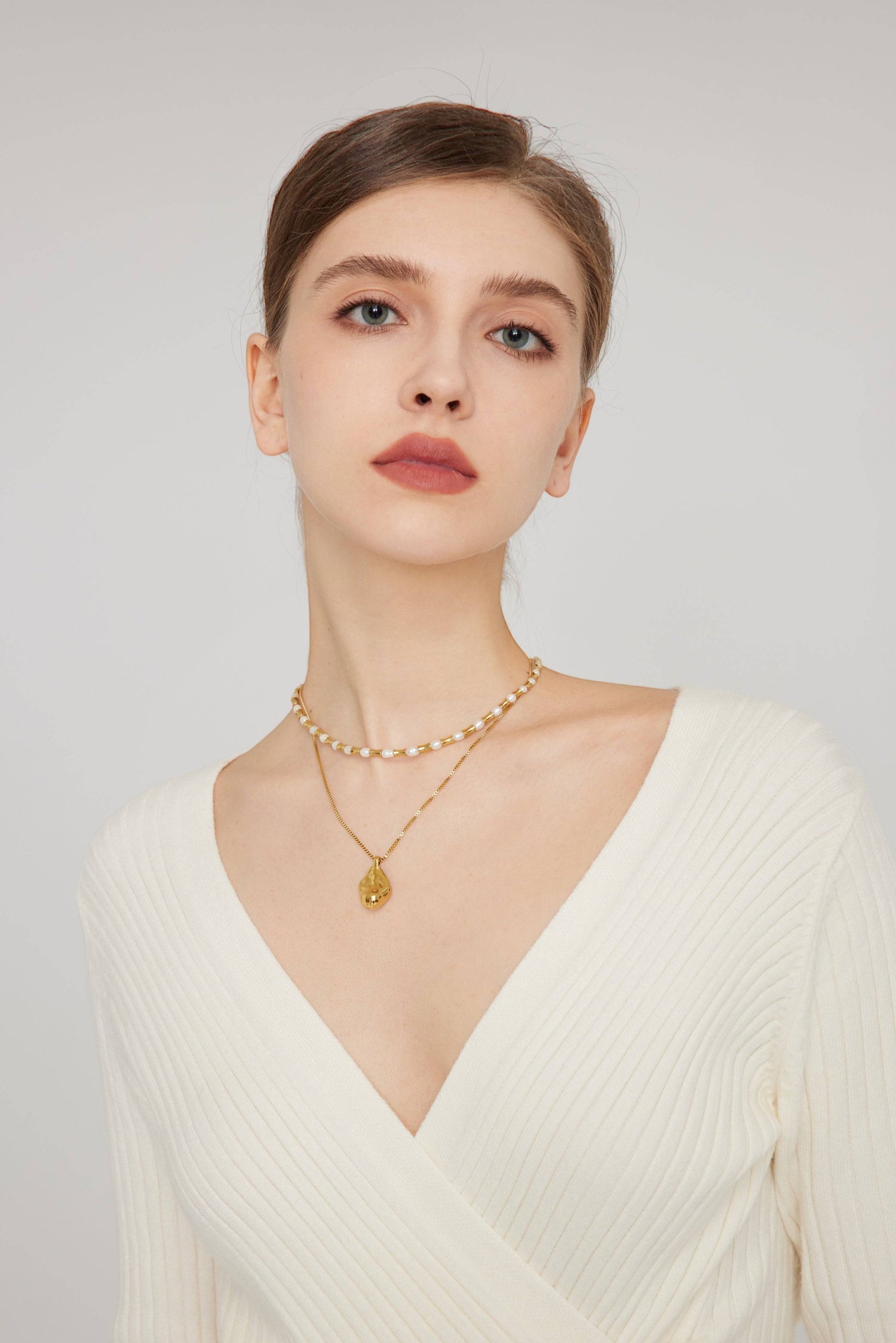 a woman wearing a white sweater and a gold necklace