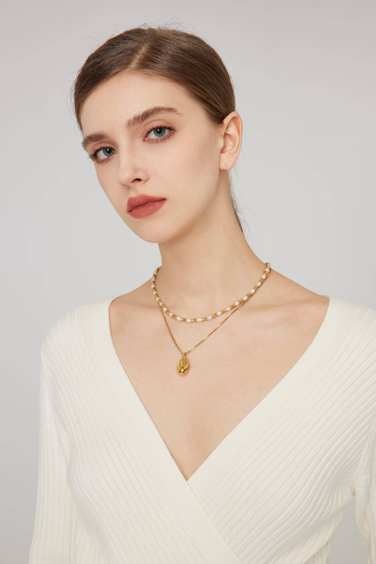 a woman wearing a white top and a gold necklace