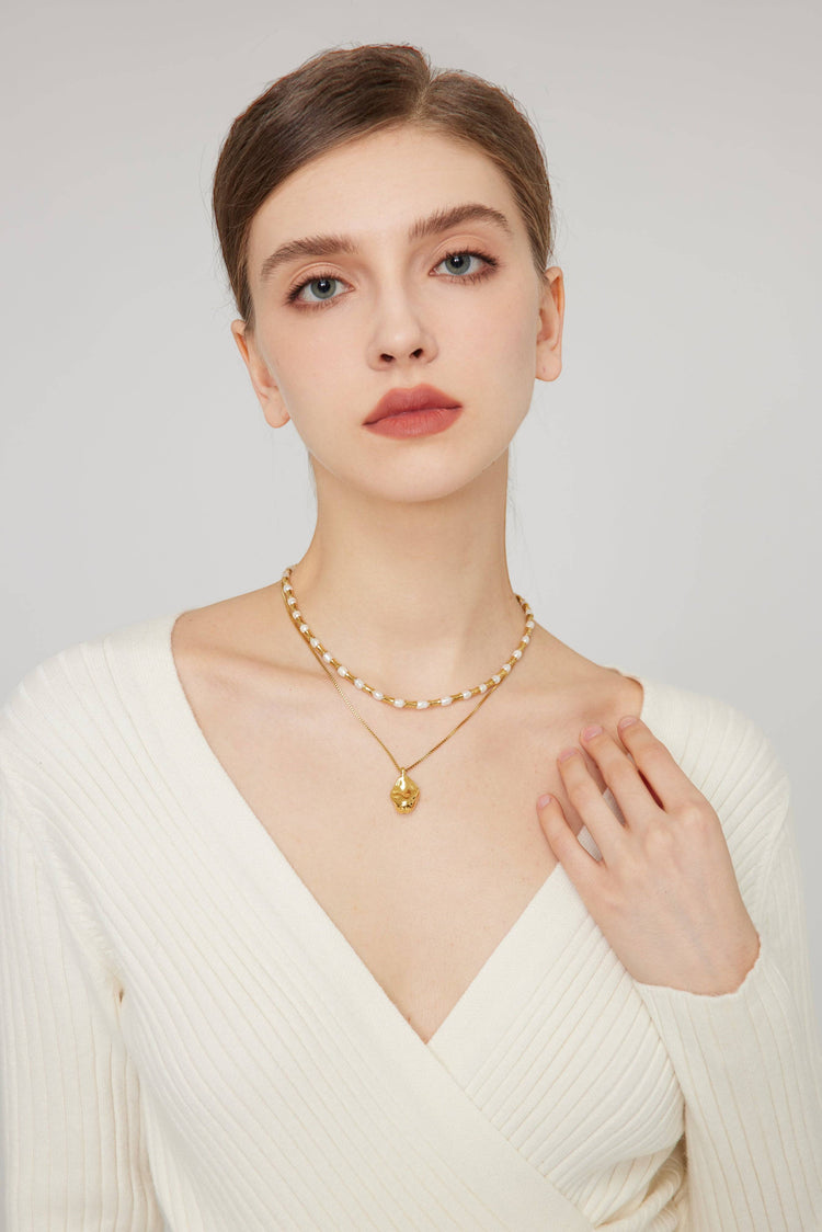 a woman wearing a white sweater and a gold necklace