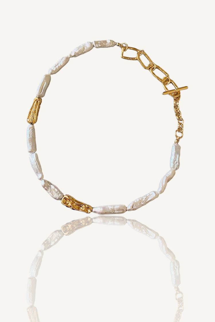 a gold and white beaded bracelet on a white background