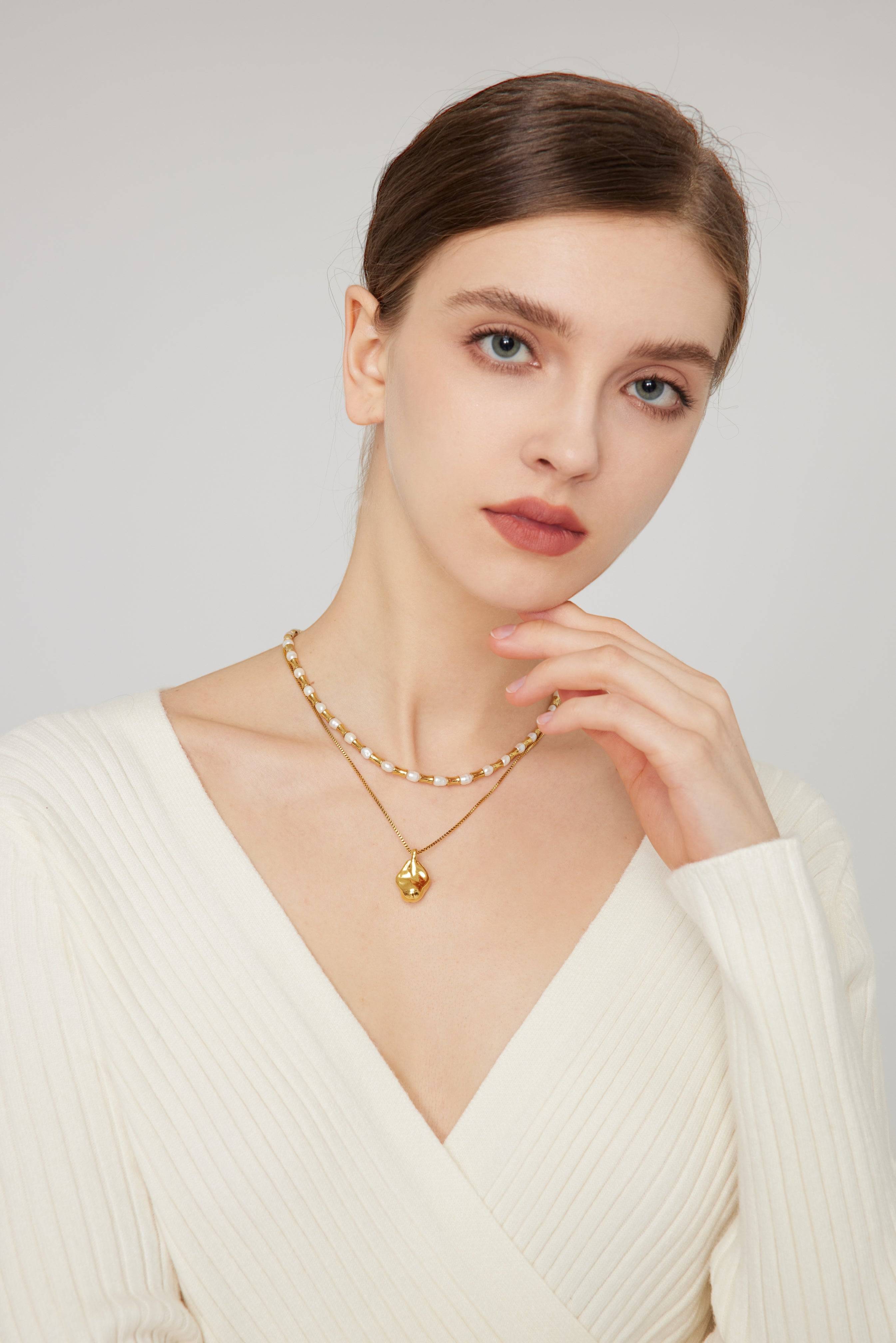 a woman wearing a white sweater and a gold necklace